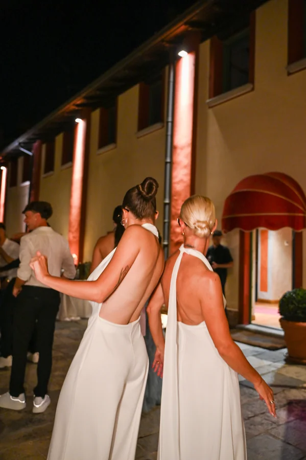 Due partecipanti in abiti chiari durante una serata di festa all’aperto.